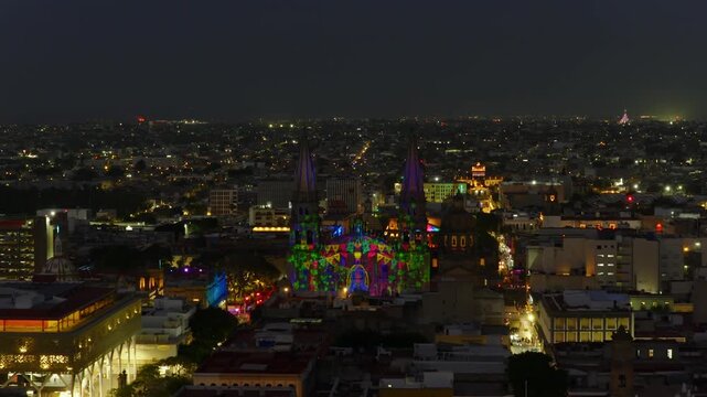 Catedral de Guadalajara illuminated by vibrant light projections celebrating Jalisco traditions and cultural icons at Aluzinante light sow. Dolly in nighttime aerial