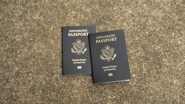 Two isolated American diplomatic passports on cement, no person