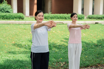 Two women practice stretching in a park embracing wellness and active lifestyles Fitness outdoors