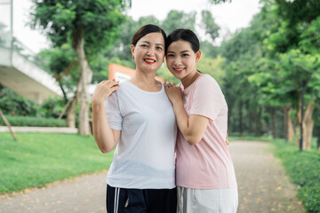 Smiling mother and daughter embracing affectionately in a green outdoor setting Bonding moment