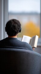 Reading Retreat: A person lost in a book, headphones on, seated comfortably, absorbing a story in a moment of solitude and focused immersion. 