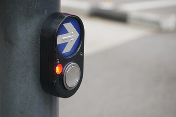 Pedestrian signal button at urban crosswalk during daytime