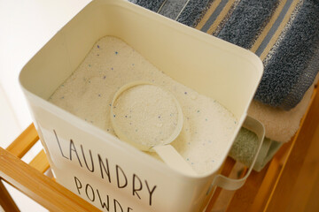 Laundry powder container with scoop and towels nearby