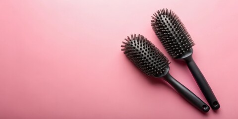 Two black round hairbrushes on pink background, ideal for hair styling and grooming.  The brushes feature soft bristles for detangling and styling.