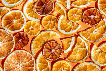 dried citrus slices in various shapes and sizes are on vivid orange background, highlighting their...
