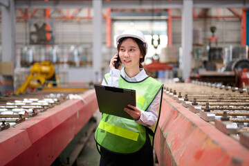 Engineer or worker talking on smartphone and holding a clipboard in the factory