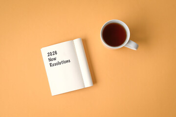 2026 New Resolutions, text on notepad. Next to a cup of coffee. Top view.