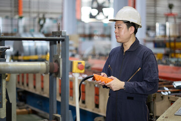 Engineer or worker operating remote switch to control machine in the factory
