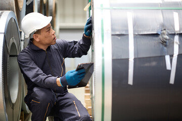 Technician or worker working on tablet and checking Sheet metal products in the factory