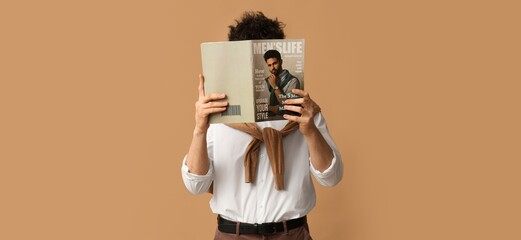 Young man with magazine on brown background