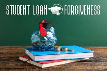 Piggy bank with graduation hat, coins and books on table near green blackboard. Student loan...