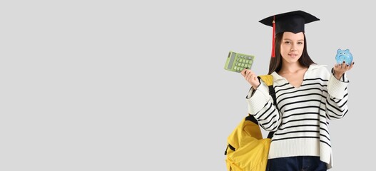 Female student in graduation hat holding calculator and piggy bank on light background with space for text. Education savings concept