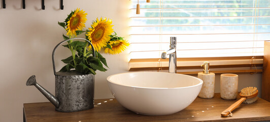 Sunflowers in watering can on table in bathroom