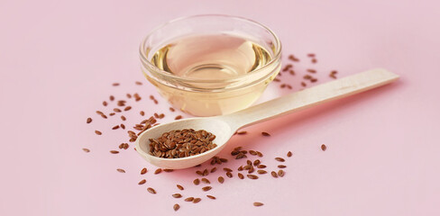 Bowl with flax oil and spoon of seeds on pink background
