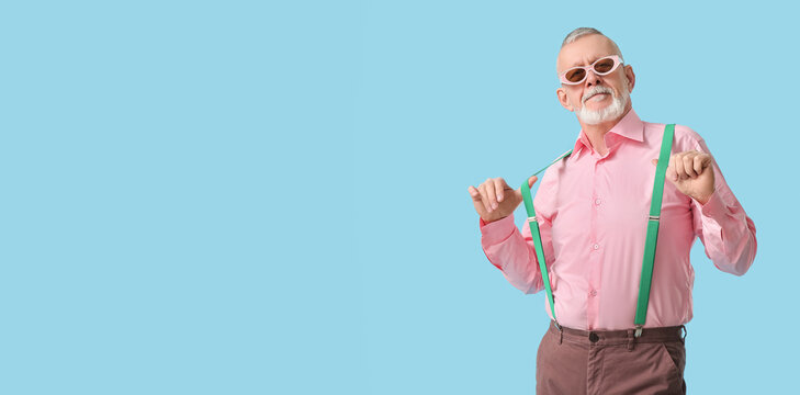 Happy senior man in sunglasses with suspenders on blue background. National Grandpa Day