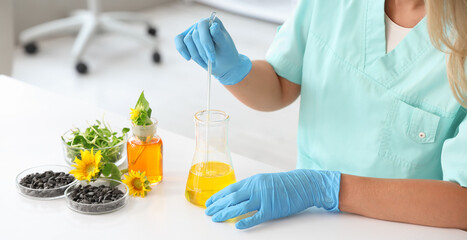 Female scientist with flasks of samples, sunflower seeds and sprouts working in laboratory, closeup