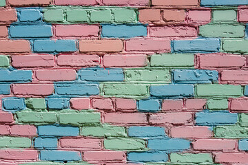 vibrant wall made bricks painted in soft pastel colors like pink, blue, and green. this urban art...