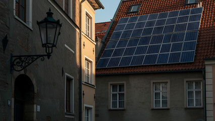 Fototapeta premium Solar panels installed on the roof of a historic European building, showing the union of old architecture and renewable energy.