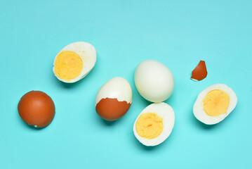 Tasty boiled eggs with halves and shells on blue background