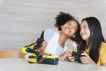 Happy Kids Exploring STEM with a Robotic Arm Kit, Young Diverse Girls Learning Robotics and Engineering Together, Two Girls Engaged in Robotics Education