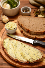 Board of bread slices with fresh butter and different spices on wooden background