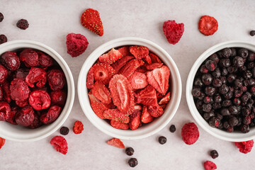 Composition with bowls of tasty freeze-dried berries on light background, closeup