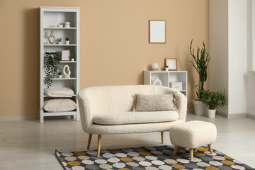 Stylish interior of beige living room with sofa, shelving units and houseplant