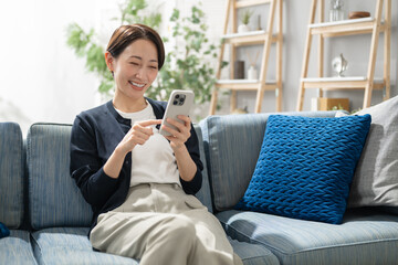 リビングでスマホを使うミドル女性