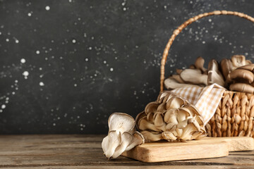 Board and wicker basket with fresh oyster mushrooms on wooden table
