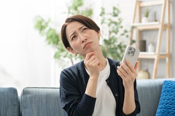 スマホを持って悩む女性