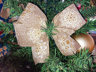 A decorated fabric bow used to decorate a Christmas tree, with a blurred background