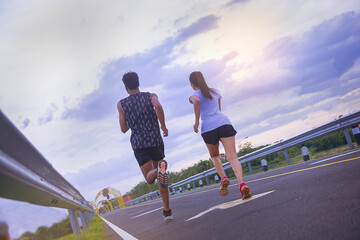 Silhouette of young couple running together on road across the bridge. Couple, fit runners fitness runners during outdoor workout