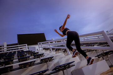 Young woman running sprinting up stairs at stadium. Fit runner fitness runner during outdoor workout. Selected focus