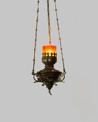 An antique metal and glass chandelier is lit, hanging from the ceiling by chains