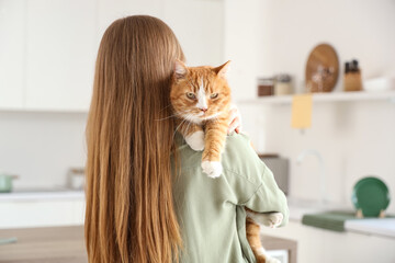 Young woman with cute red cat in kitchen, closeup