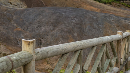The unique 23 coloured earth of Mauritius. Colorful sand hill. There is an unpainted wooden railing...