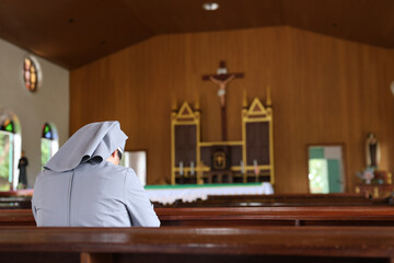 Christian nuns with white robes praying in a church.