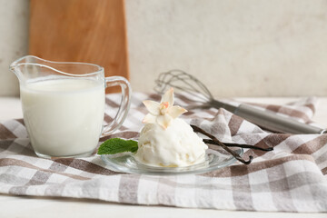 Napkin, jug of milk and plate with tasty vanilla ice cream on table