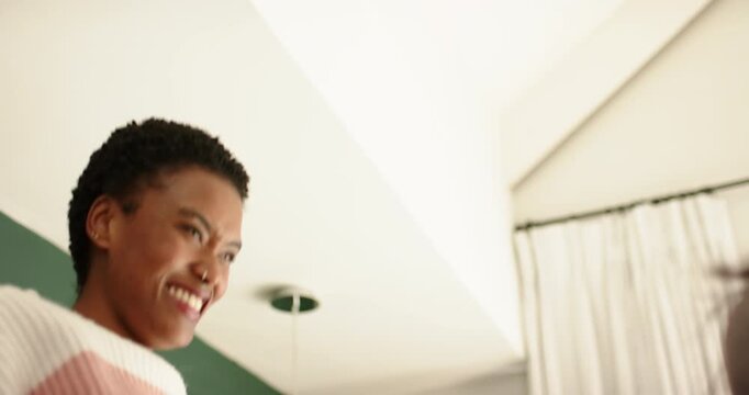 African American female friends sharing playful high-five after teasing near curtains and light