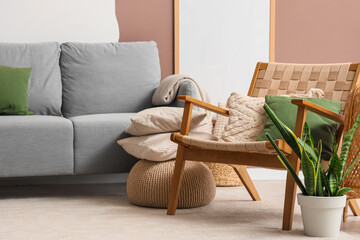 Armchair with cushions and plant in interior of living room