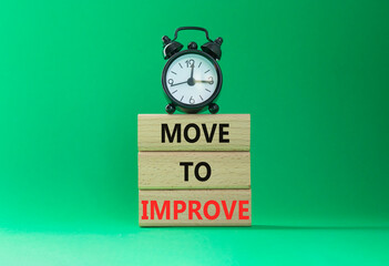 Move to Improve symbol. Concept words Move to Improve on wooden blocks. Beautiful green background with alarm clock. Business and Move to Improve concept. Copy space.
