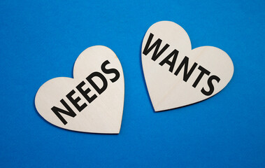 Wants and Needs symbol. Concept word Wants and Needs on wooden hearts. Beautiful blue background. Business and Wants and Needs concept. Copy space