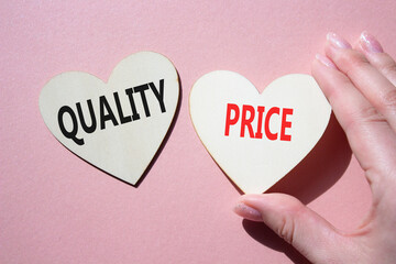 Price or Quality symbol. Concept word Price or Quality on wooden hearts. Businessman hand. Beautiful pink background. Business and Price or Quality concept. Copy space