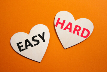 Easy or Hard symbol. Concept word Easy or Hard on wooden hearts. Beautiful orange background....