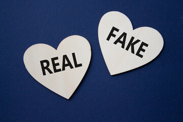 Real or Fake symbol. Concept word Real or Fake on wooden hearts. Beautiful deep blue background. Business and Real or Fake concept. Copy space
