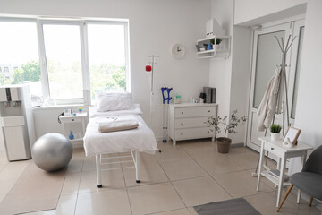 Interior of hospital ward with bed, drawers and cooler