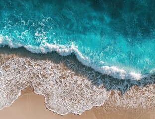 High-angle view of turquoise waves crashing on beige sand