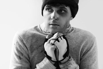 Frozen young homeless man on light background, closeup