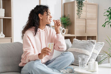 Young African-American woman taking fish oil at home