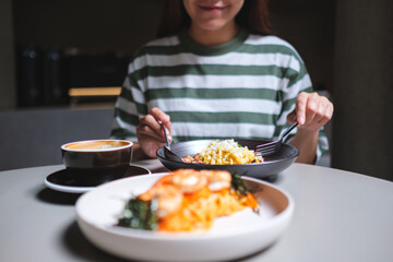 Closeup image of a woman eating spaghetti on dining table